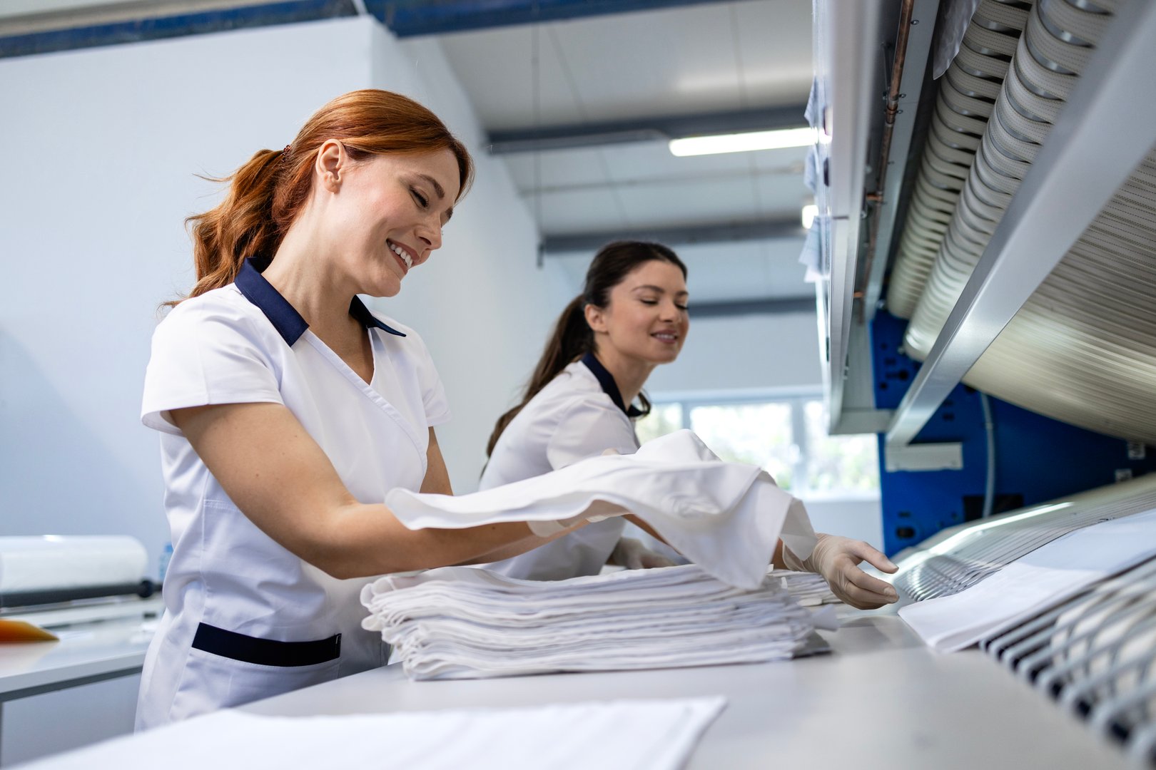 Female employees folding clean laundry and preparing for delivery