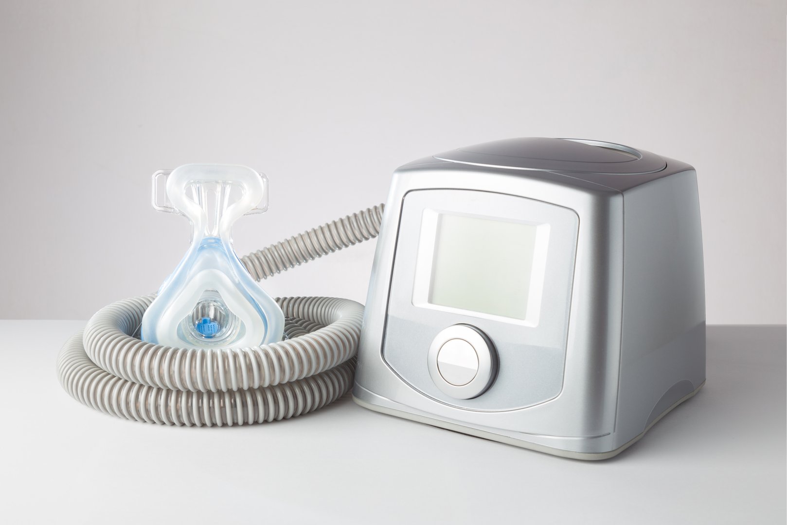 Sleep Apnea CPAP machine with hose and head hear mask, on white table