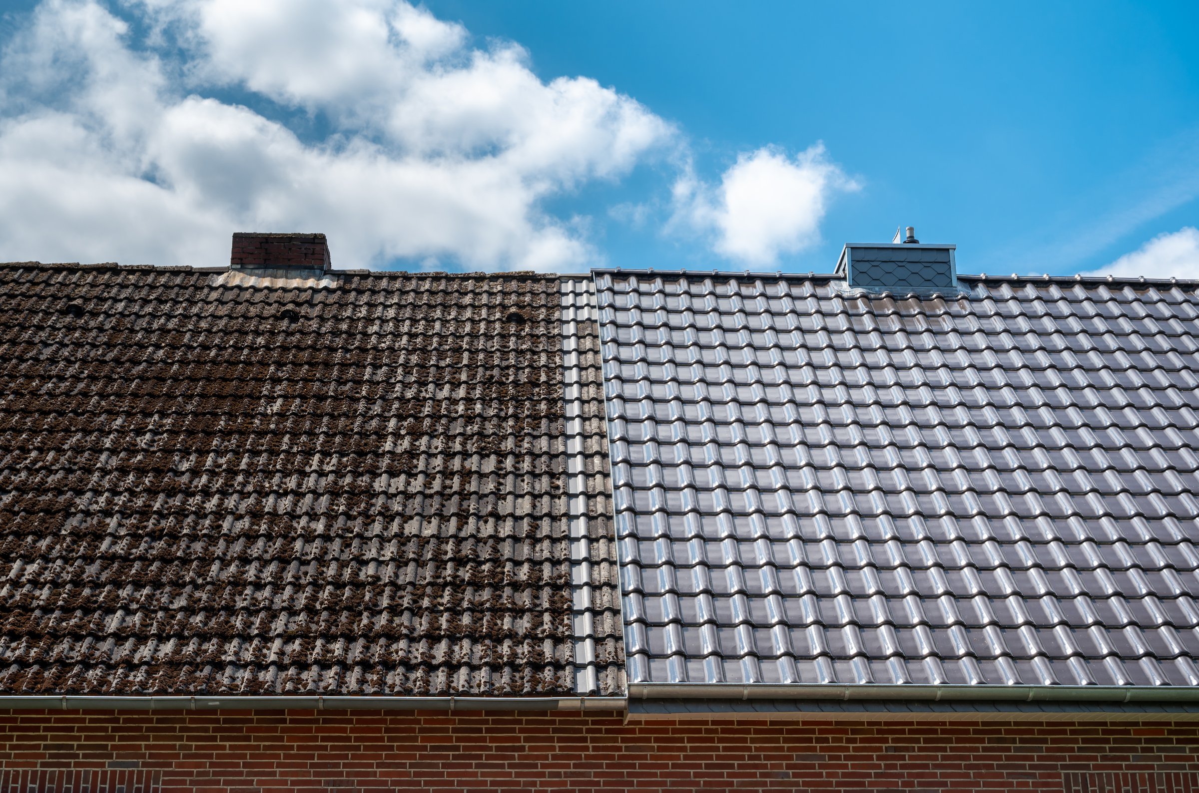 A half cleaned house roof shows the before and after effect of a roof cleaning
