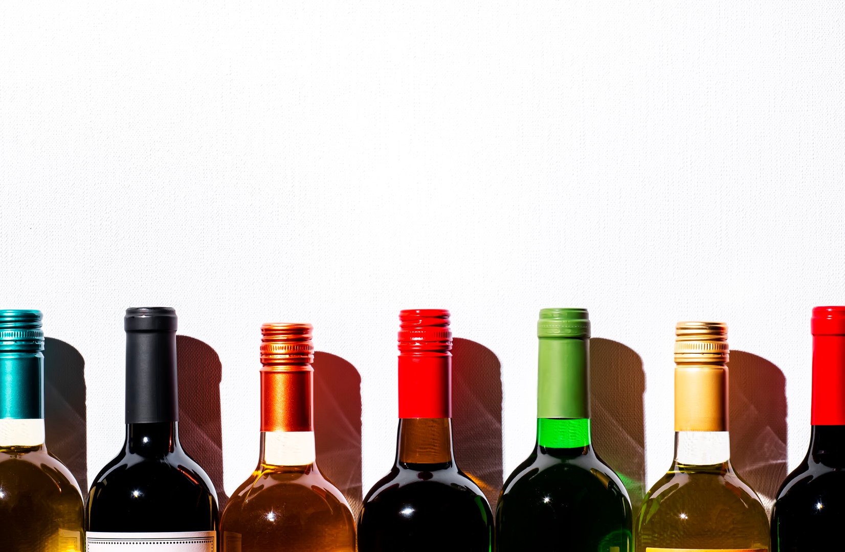 Wine bottles collection row in wine shop, restaurant or bar on white background. Multi-colored wine bottle necks