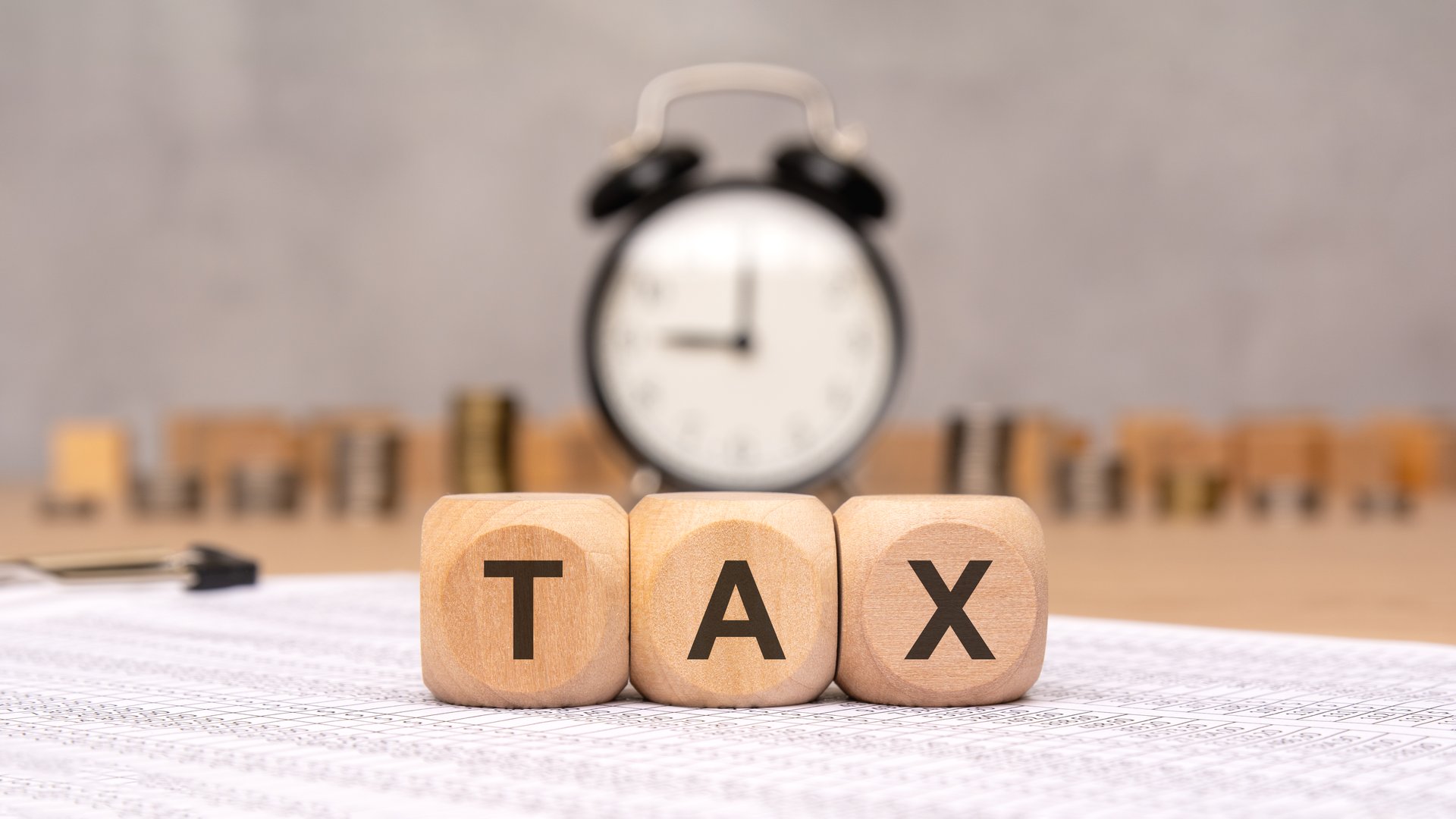 an image illustrating tax season urgency with blocks spelling TAX and a clock, emphasizing timesensitive filing