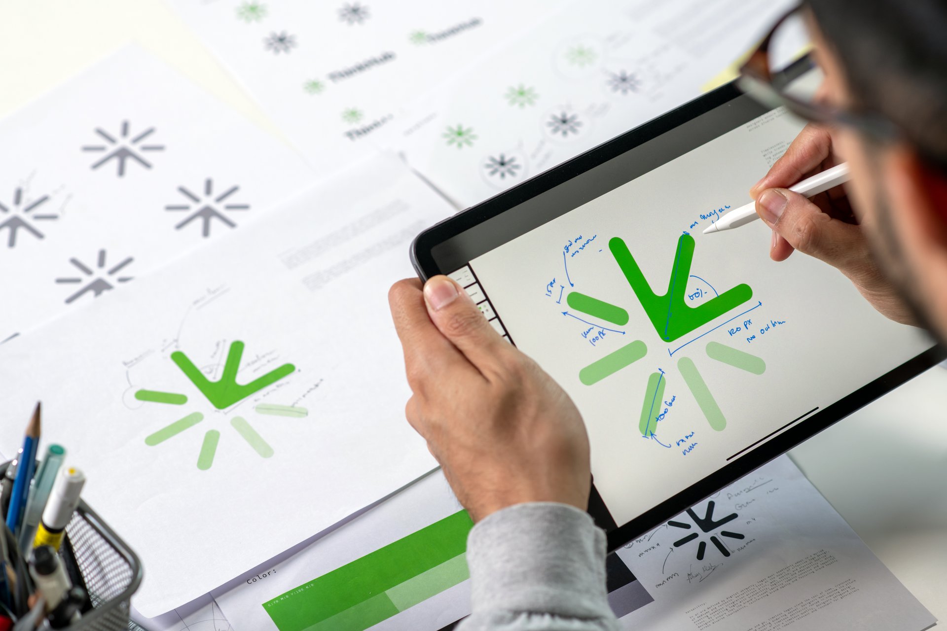 Close-up shot of a graphic designer making notes on logo designs, using a tablet, designing logos, and showcasing the corporate identity and logo design process.
