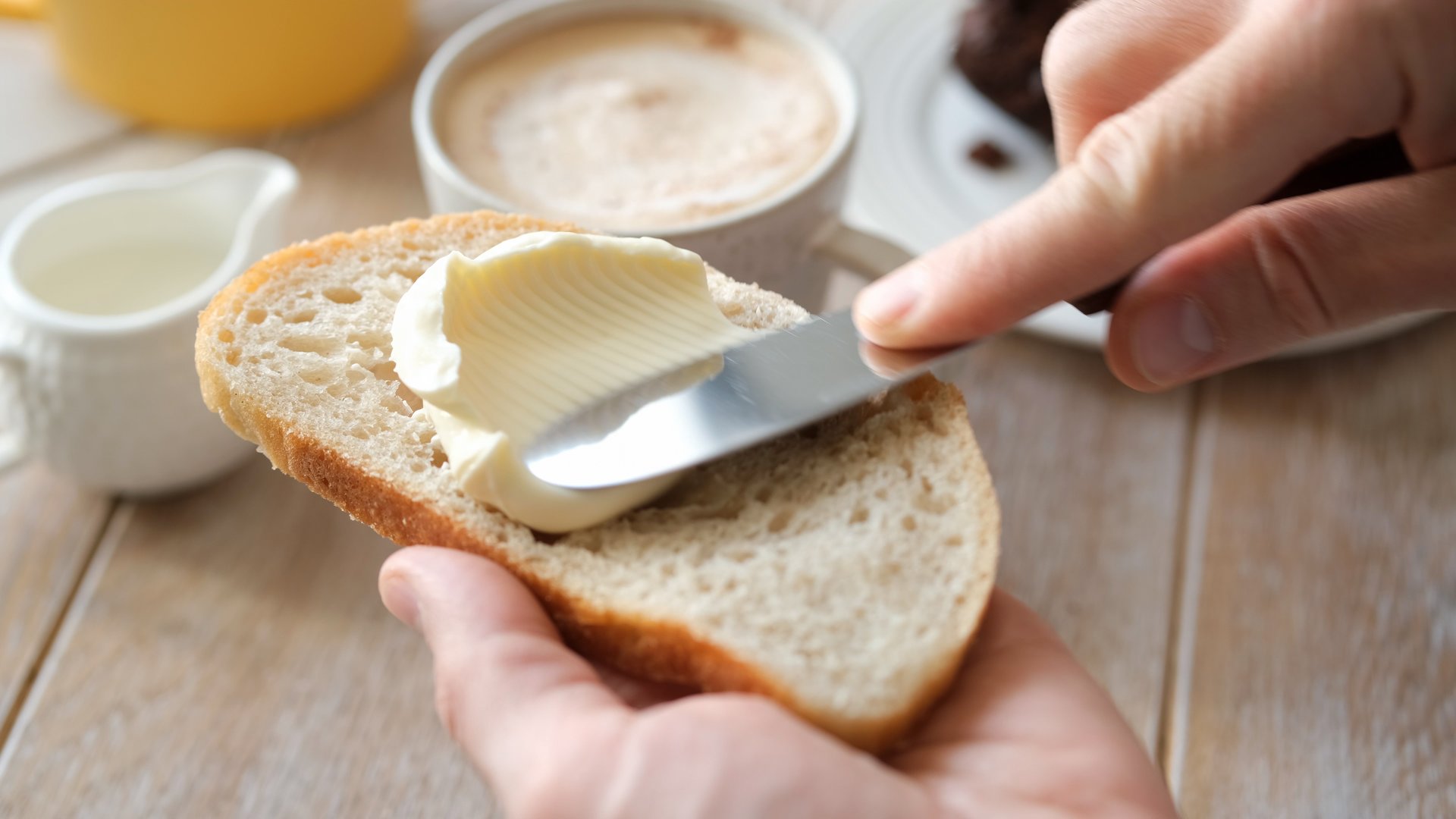Spreading soft butter on white bread toast, closeup view