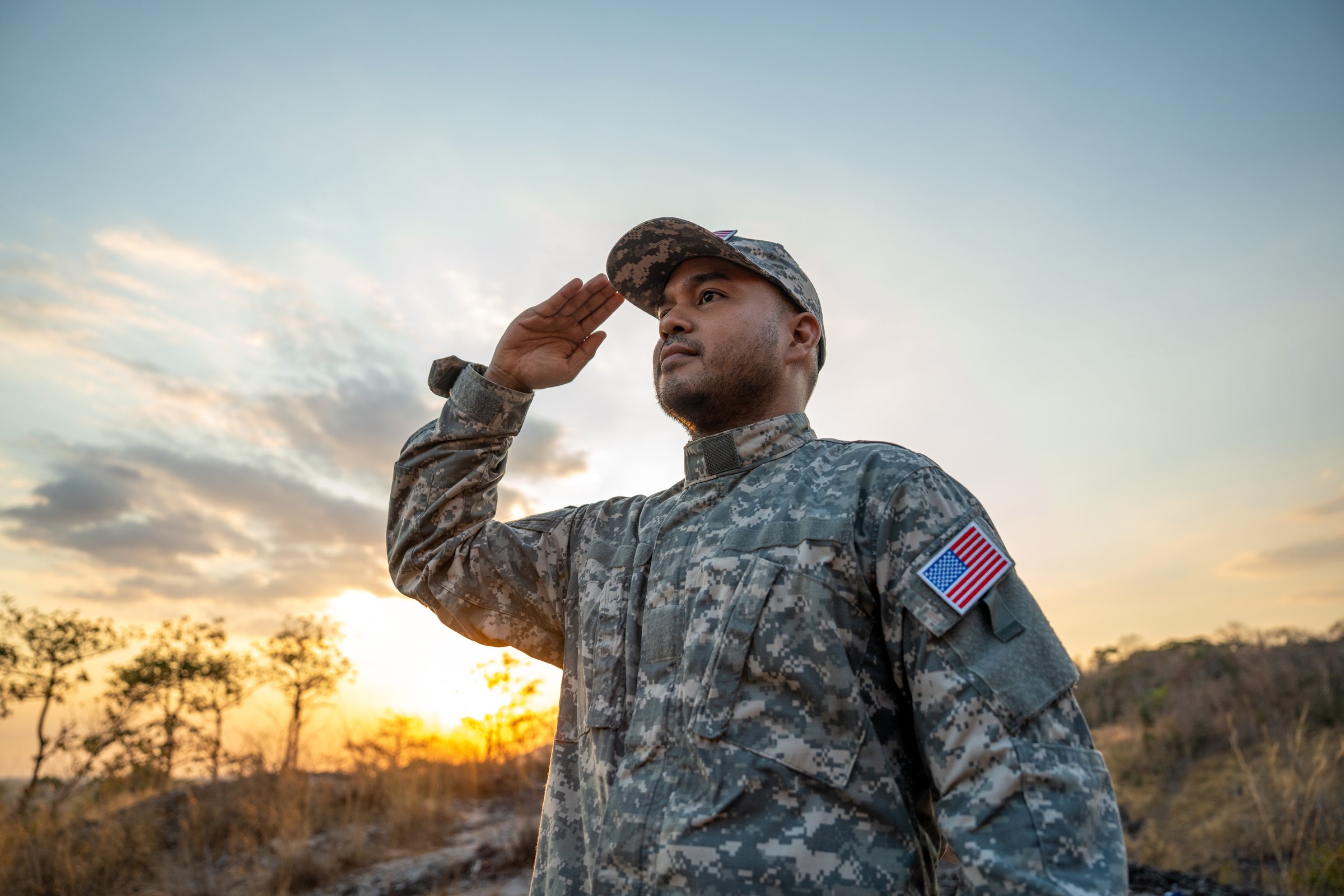 Us Army veteran honors Veterans Day. Man soldier adjusts the US military patch before duty. A US soldier with an American flag patch on his uniform prayers for Memorial Day. Independence Day
