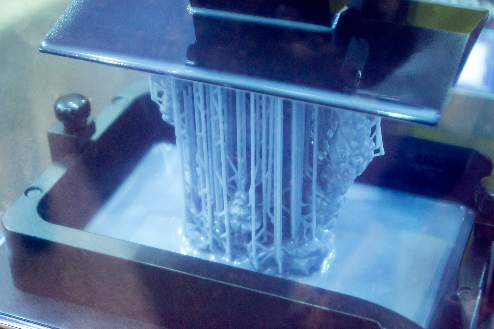 Working of photopolymer sla 3D printer. Platform with building object lowered into liquid photopolymer resins and hardened under ultraviolet laser. Progressive additive technology. 3D printer printing