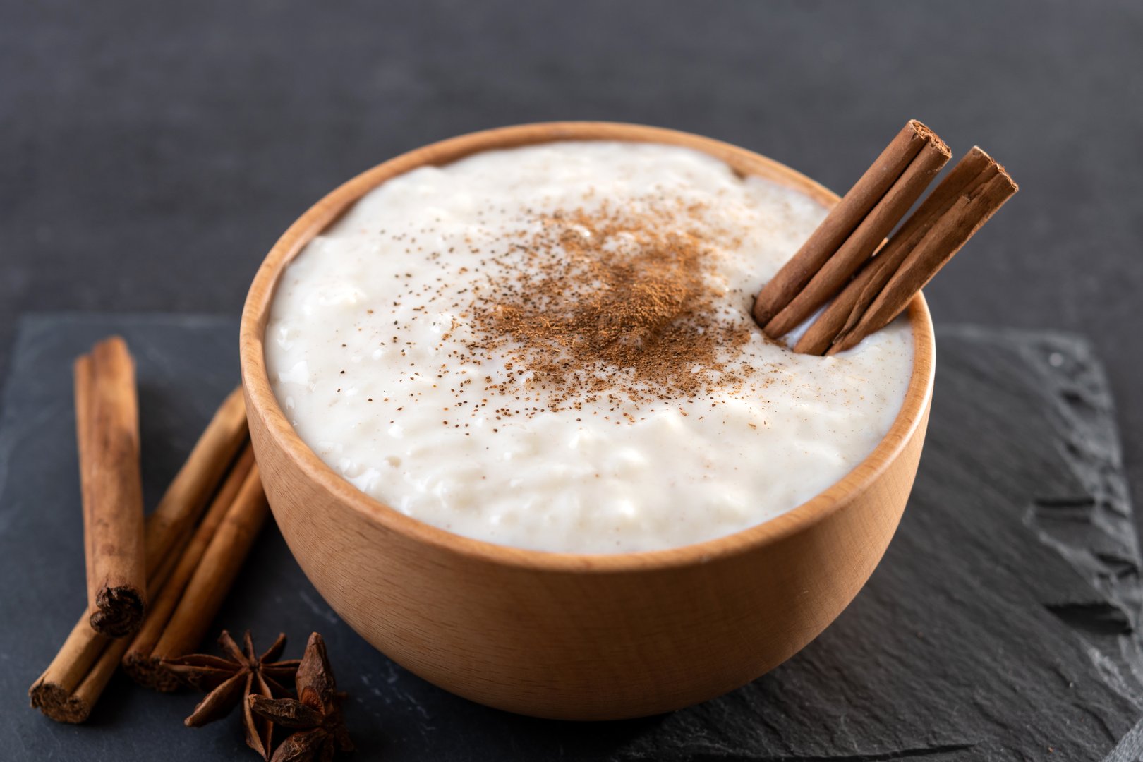 Rice pudding on wooden bowl on black slate background