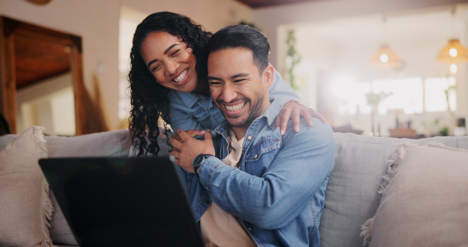 Sofa, couple and hug with laptop for laughing, streaming online and check movie for bonding together. Home, woman and man with technology for entertainment website, platform and happiness with love