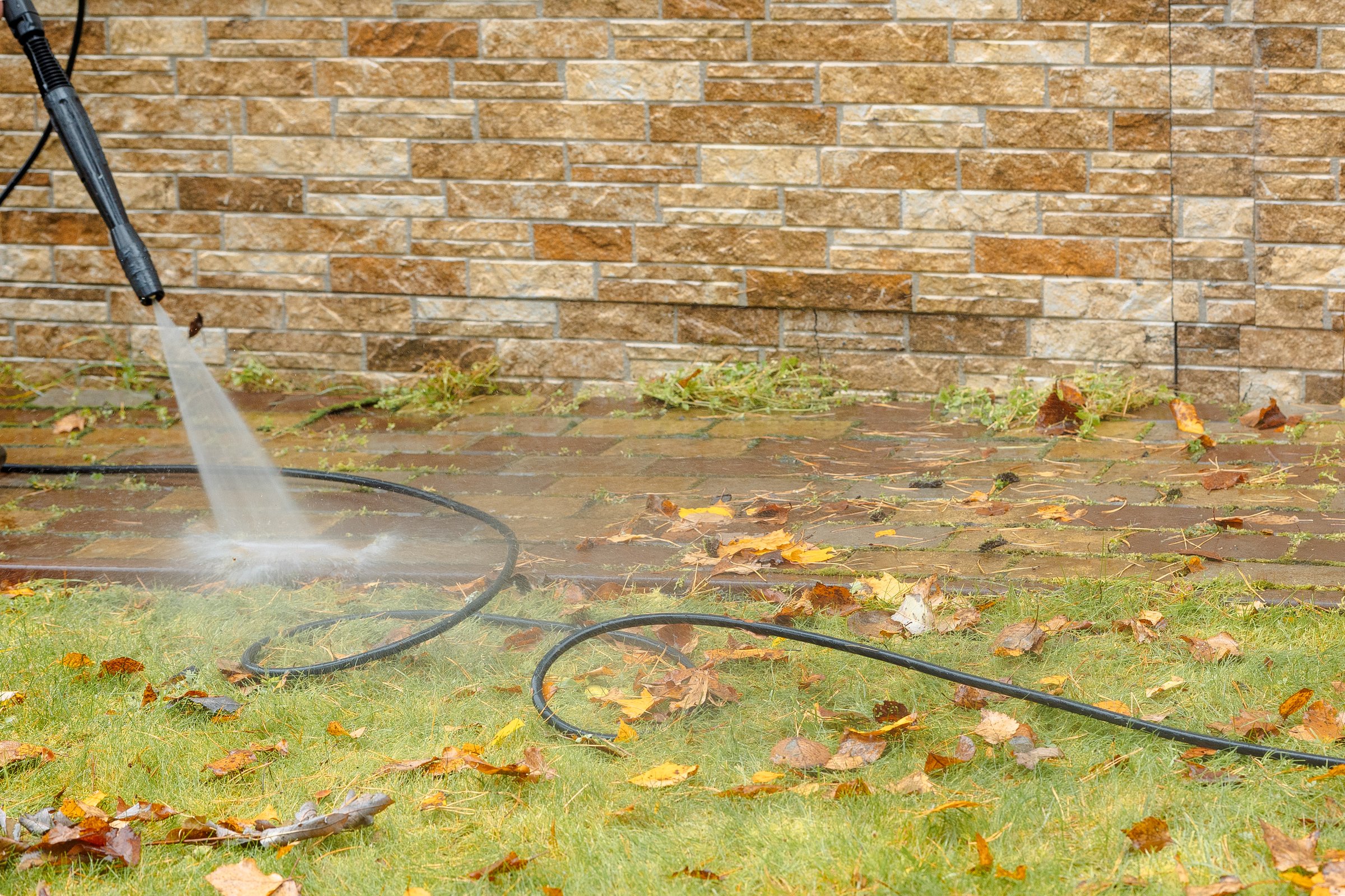 Man cleaning street with high pressure power washer, washing stone garden paths. High quality photo
