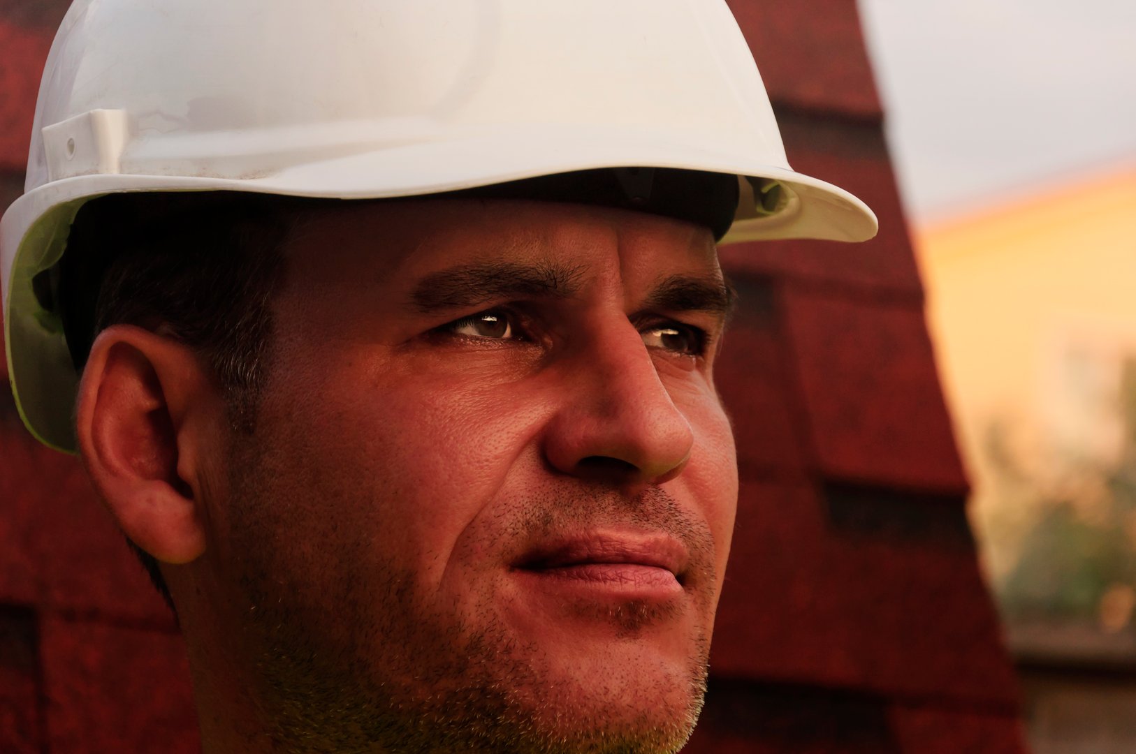 Roofing work, Builder in white hard hat of the engineer in the background the roof of a country house