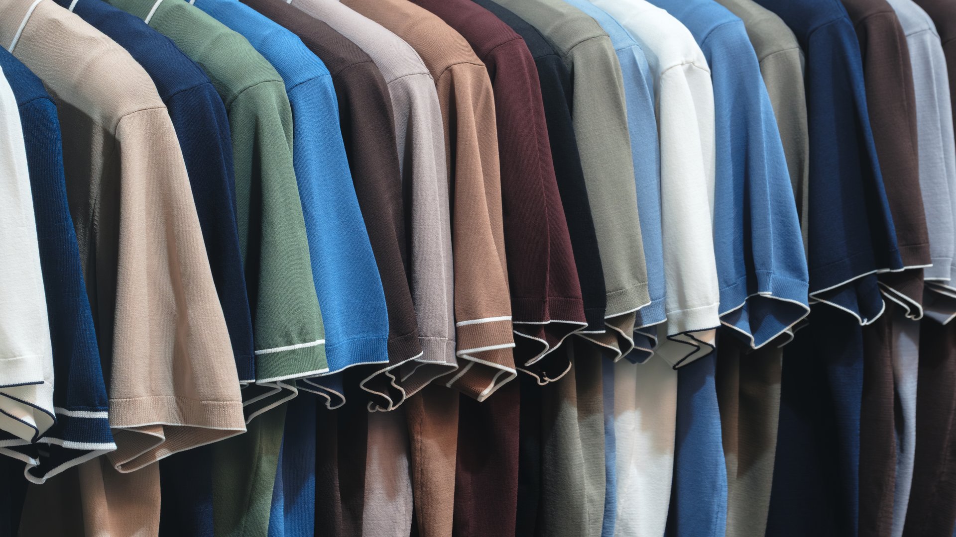 A row of clothes hanging on a hanger, the clothes are of different colors and textures, and all neatly folded. The concept of organization and order. Clothing sale concept background