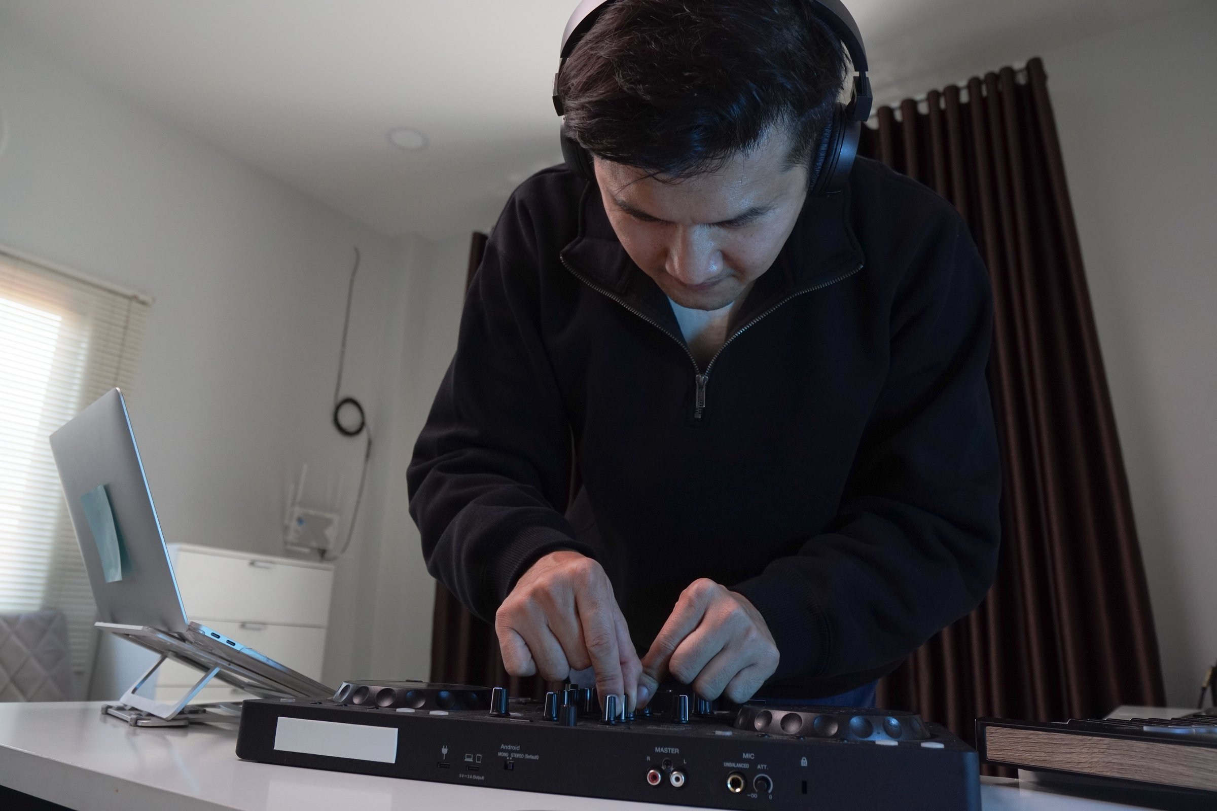 Asian DJ happily mixing and practicing his playlist at home.