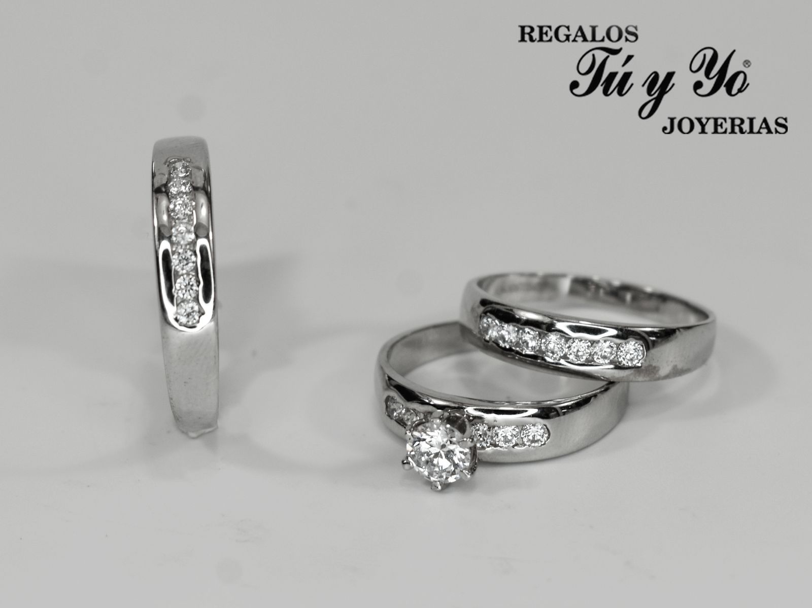 Three silver rings with diamonds, including one solitaire. Logo "Regalos Tú y Yo Joyerias" in the corner.