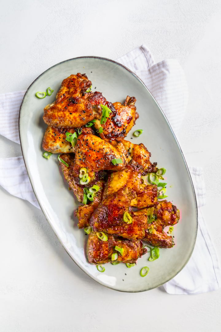 Homemade asia style chicken wings with green onions on serving plate
