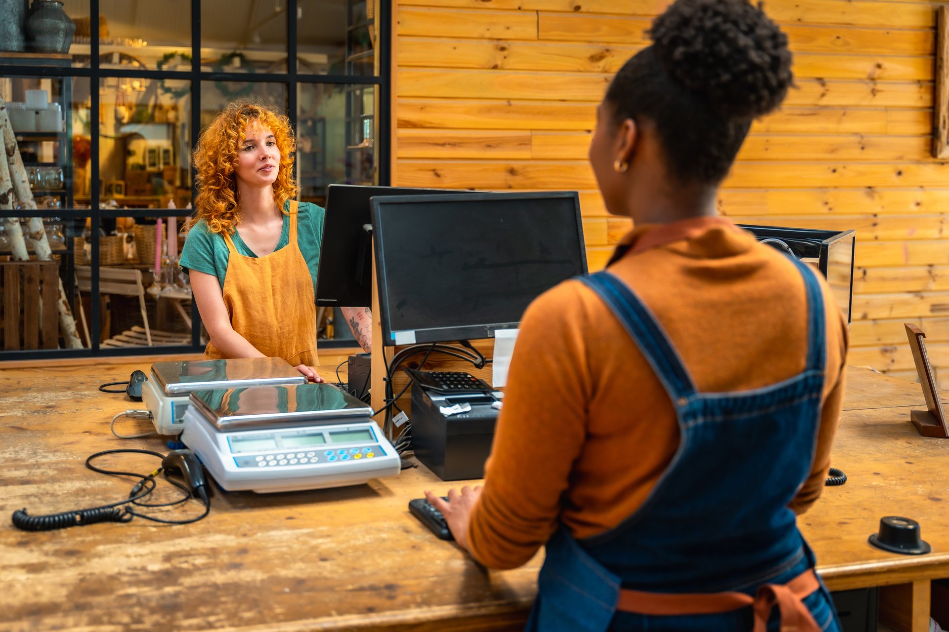 Florist assisting customer at checkout counter, using computer and scale in vibrant flower shop, facilitating a smooth transaction