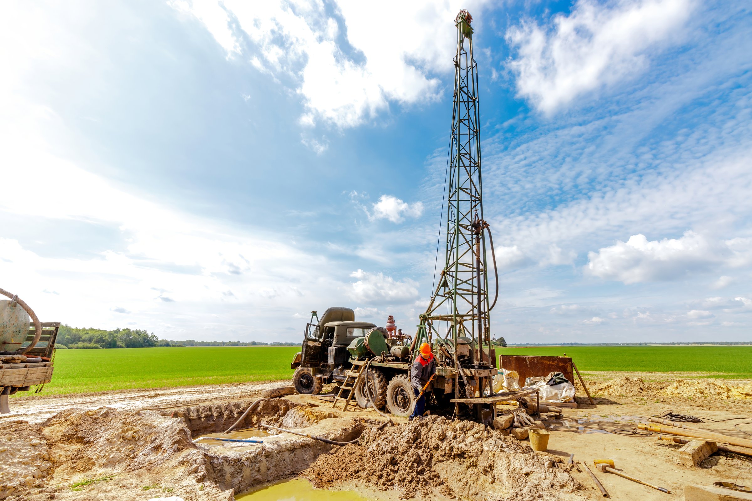 Worker drilling into the earth with his well drilling machine to extract water. Drilling equipment, drills well for water extraction.