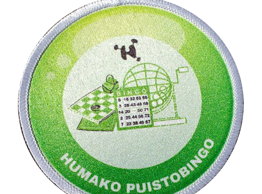 Round patch with bingo theme, featuring cards, cage, and checkerboard, labeled Humako Puistobingo on a green background.