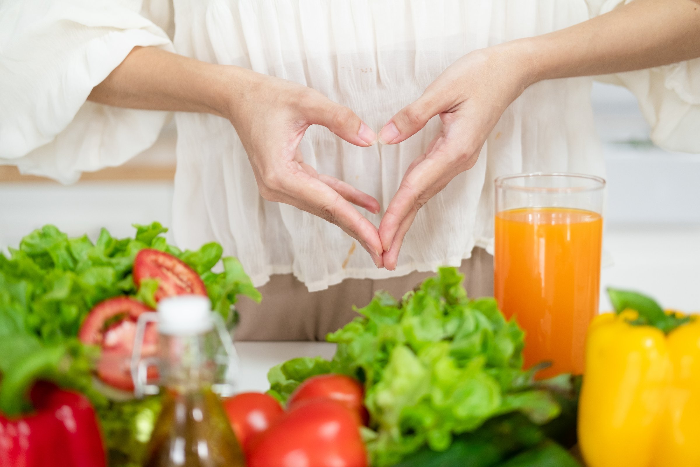 Female make shape of heart with her hands. Light summer breakfast with organic vegetable, fruits. Nutrition that promotes good digestion and functioning of gastrointestinal tract.