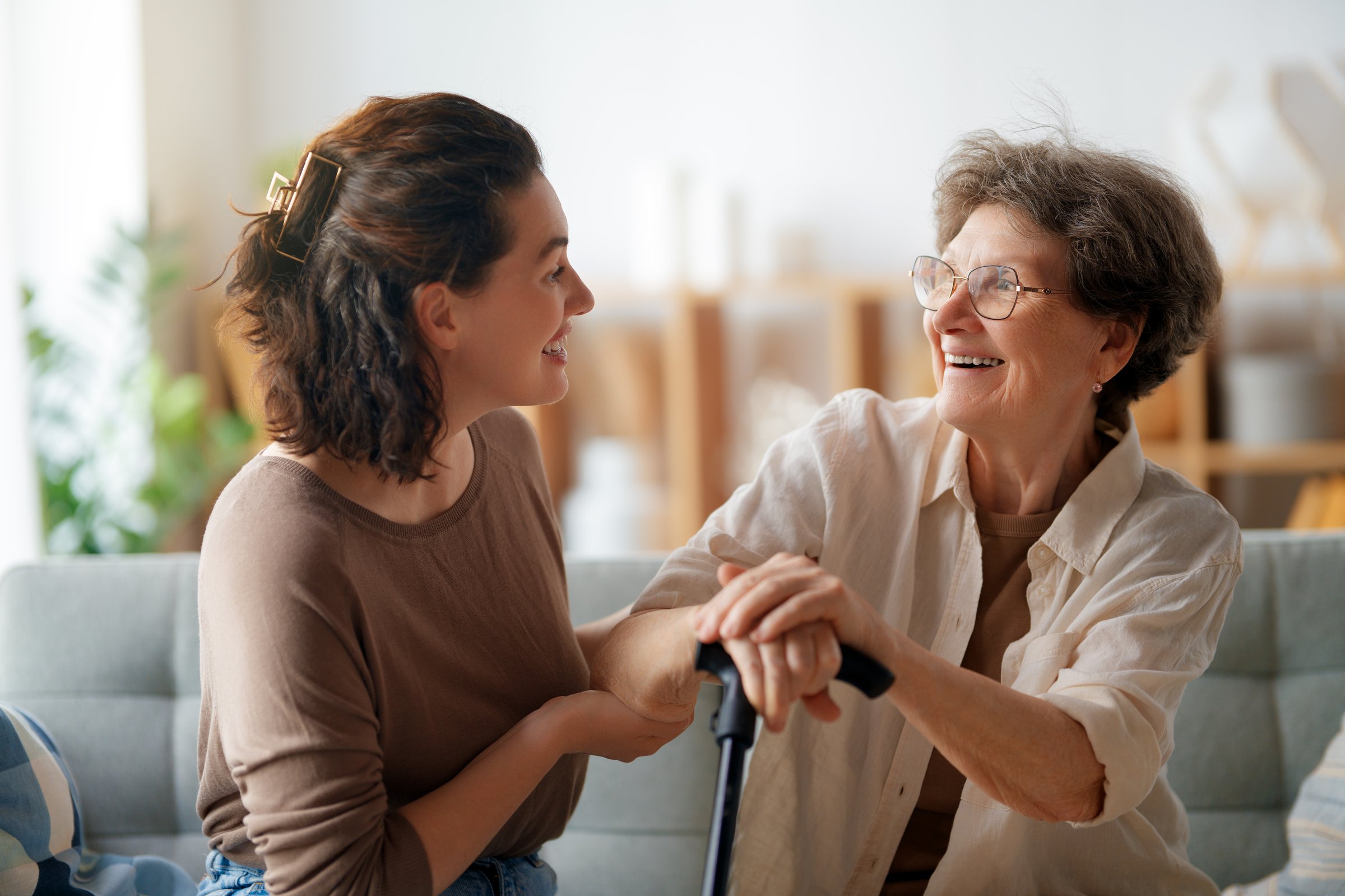 Happy patient and caregiver spending time together. Senior woman holding cane.