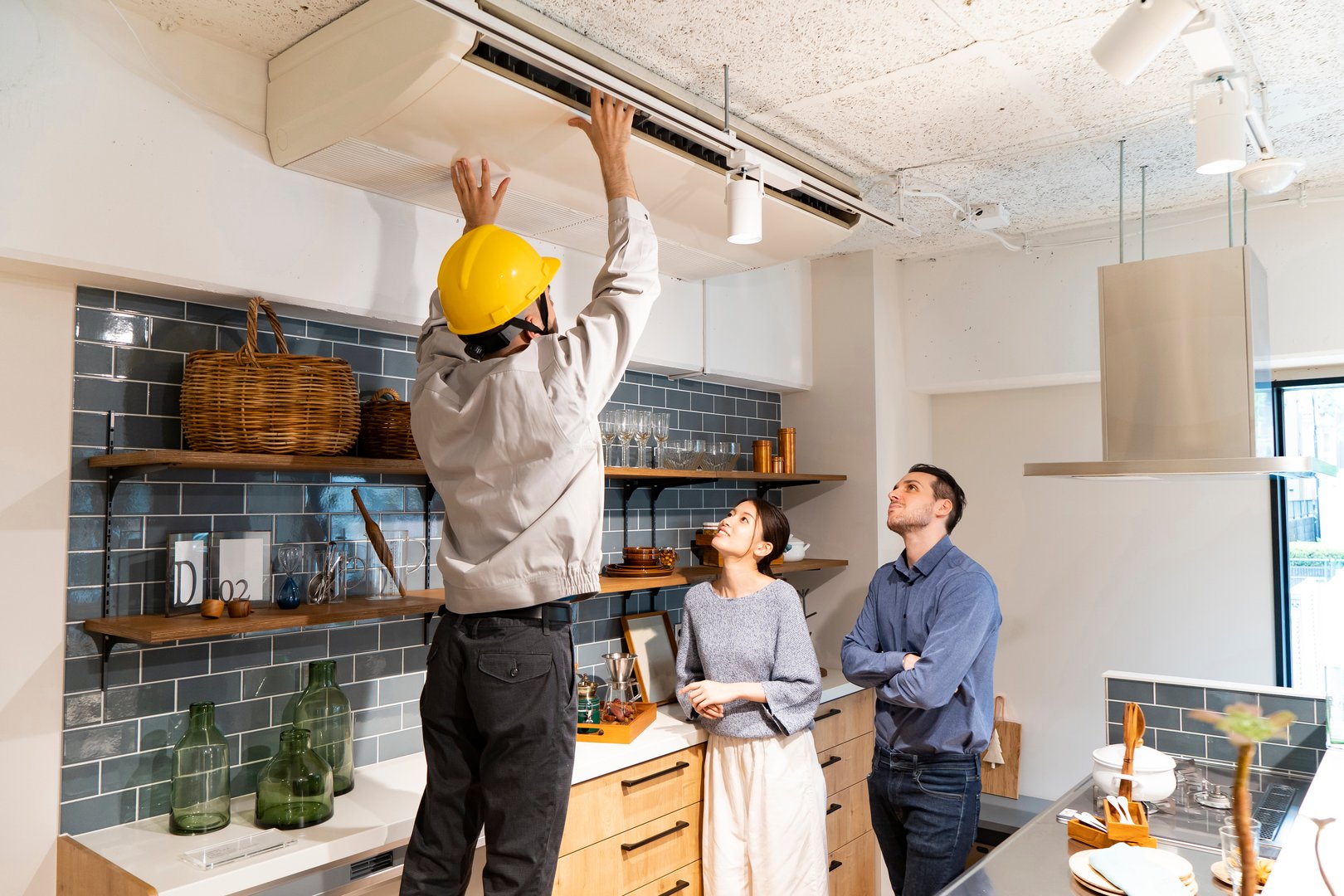 A repairman wearing a yellow helmet and checking the air conditioner