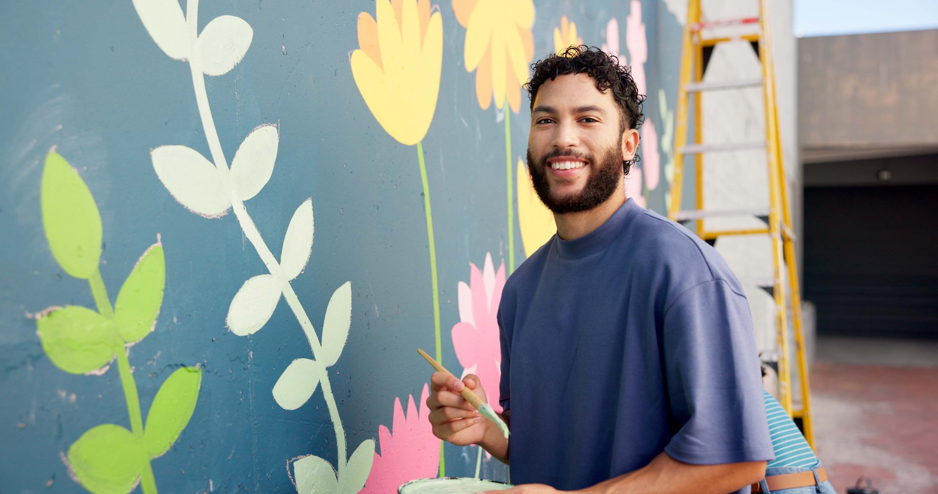 Hispanic man painting mural for community project