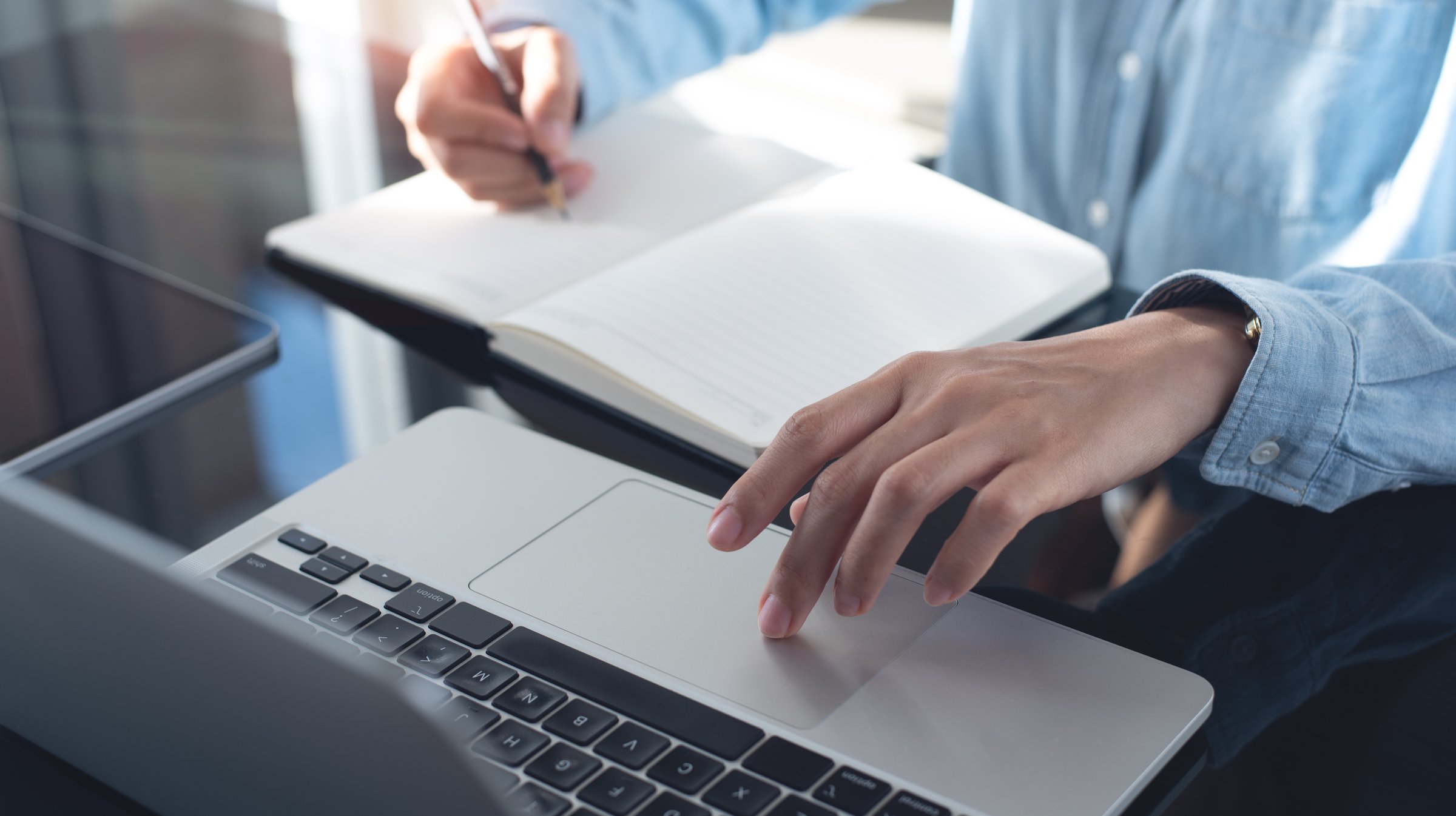 Business woman working on laptop computer and writing note on notebook. Female student searching the information on laptop computer during online studying, e-learning,  business planning