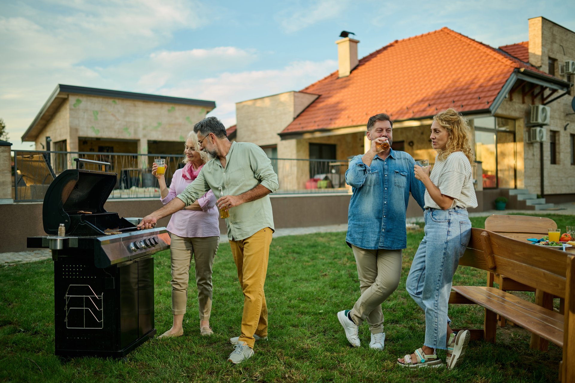 Friends enjoying a backyard barbecue party on a sunny day, grilling food and socializing happily