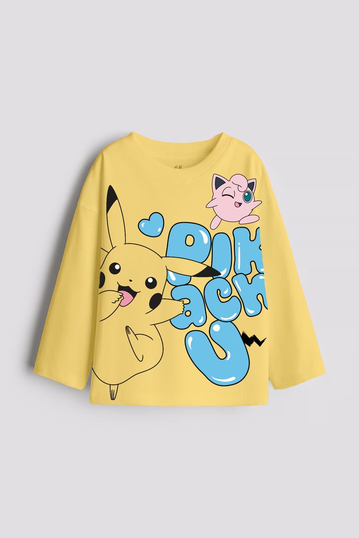 Yellow long-sleeve shirt featuring Pikachu and Jigglypuff with playful blue bubble text. Cute cartoon design.