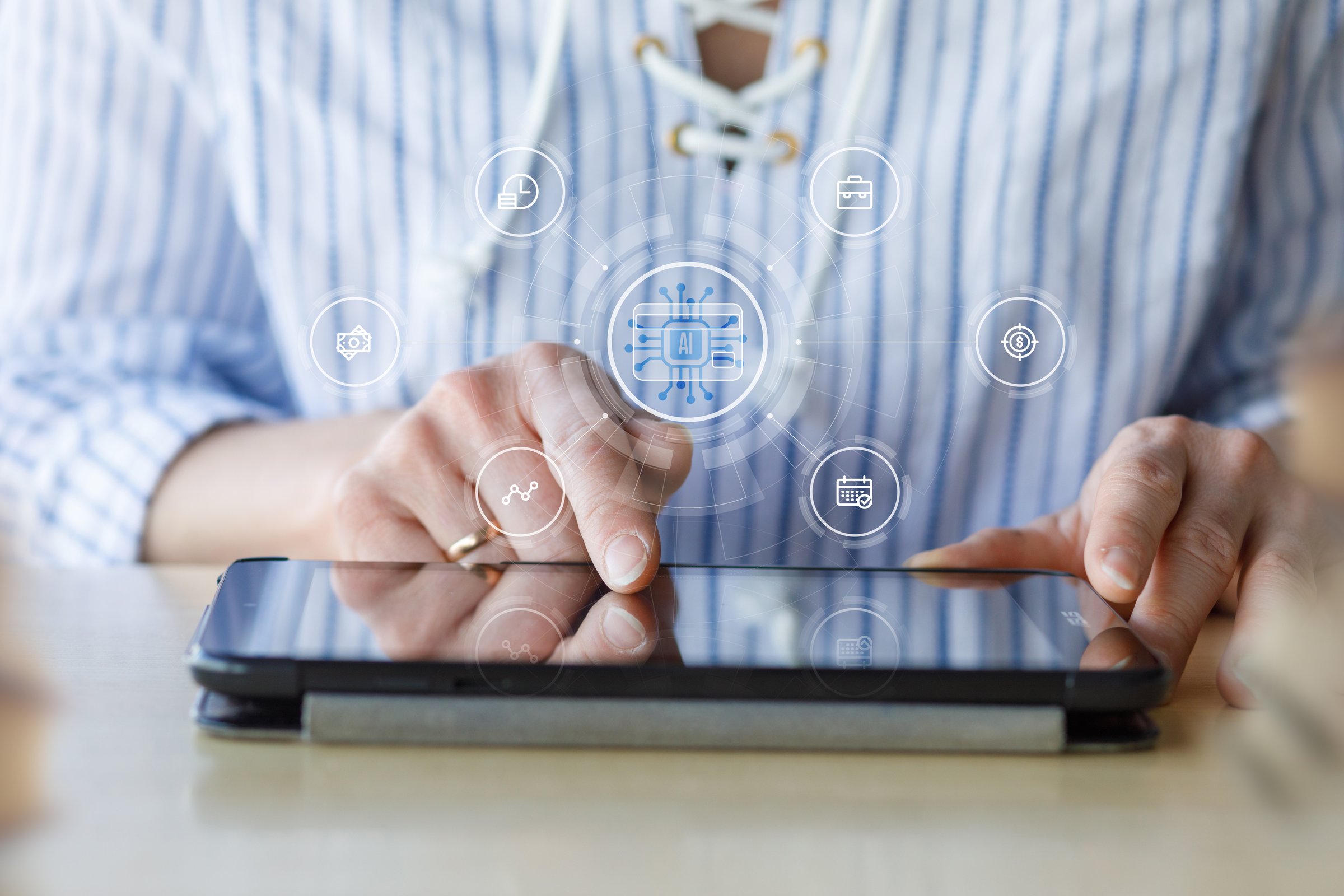 A person is interacting with a touchscreen device. Digital icons related to technology and information are visible above the screen, suggesting an online activity or app usage.