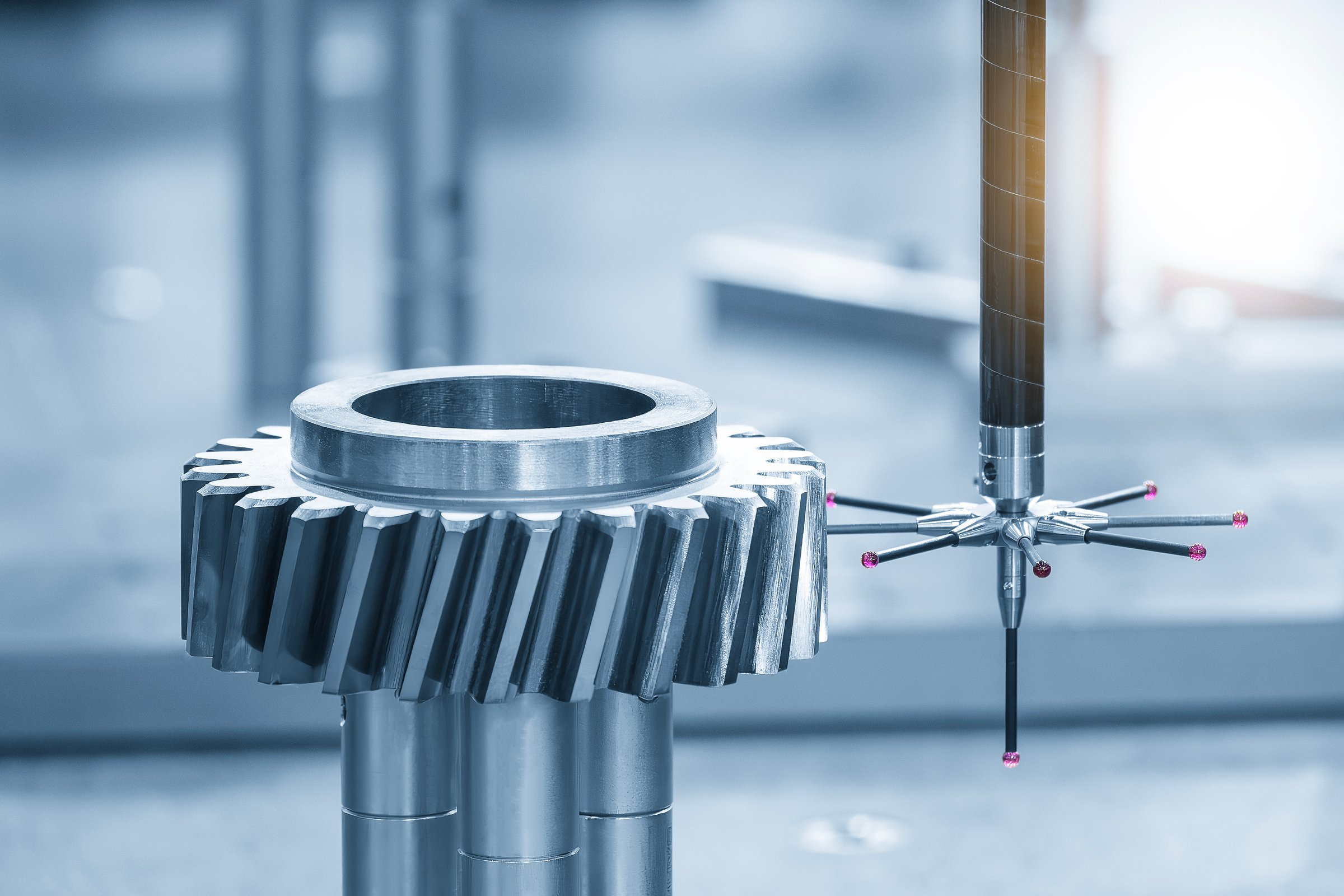 The CMM machine measuring the metal gear parts by modular probe in the light blue scene. The quality control of automotive parts with CMM machine.