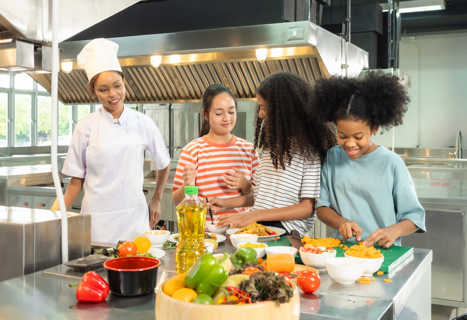 Kids children cooking group together teamwork happy fun enjoy in class learning clean culinary guid by chef supervision professional in uniform kitchen preparing food with fresh vegetables on counter.