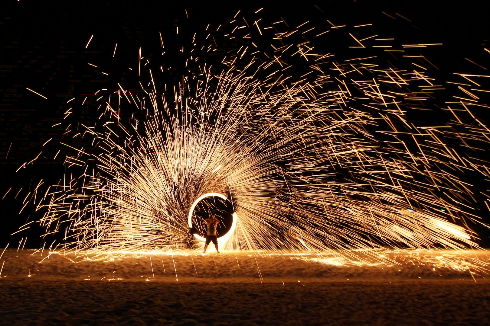 Traditional spectacular spinning illuminate torch fireball Thai fire show on the island beach at night