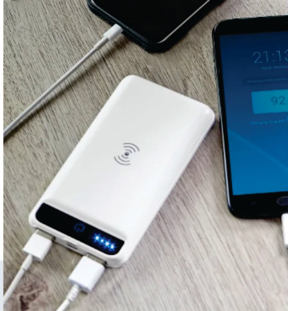 A white power bank charging two smartphones on a wooden surface. One phone displays a 92% charge level.