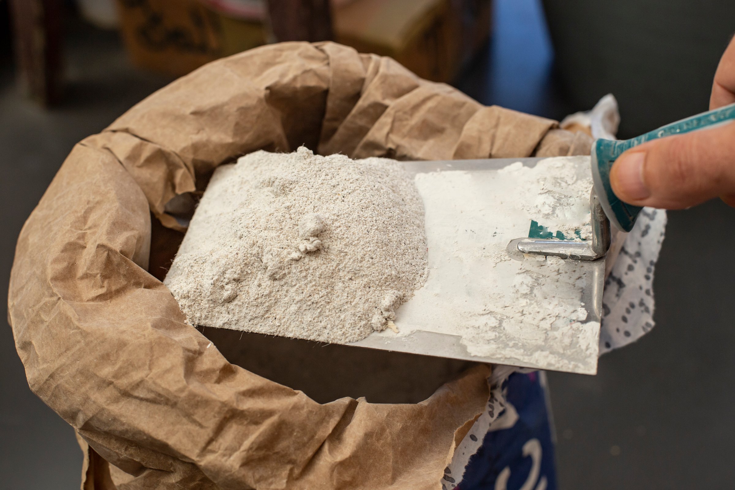 Male hand holding putty cement on a trowel from a paper bag sack, home renovation
