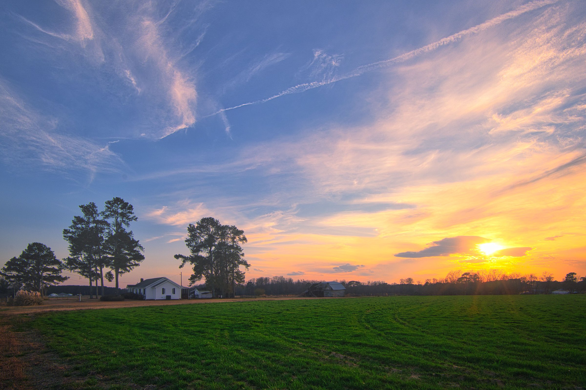 A winter landscape of an American farmhouse at sunset under a colorful cloudy blue sky in Lillington, North Carolina in the United States.