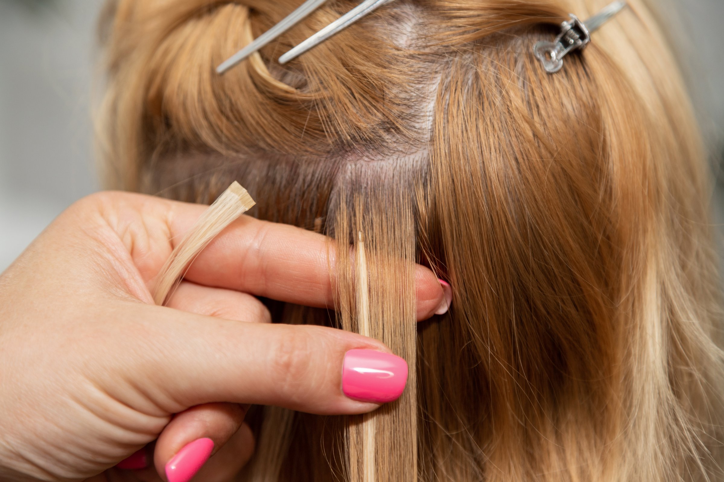 Hairdresser's hands with a strand of hair in his hands. Blonde hair extensions. A strand of hair extensions. High quality photo