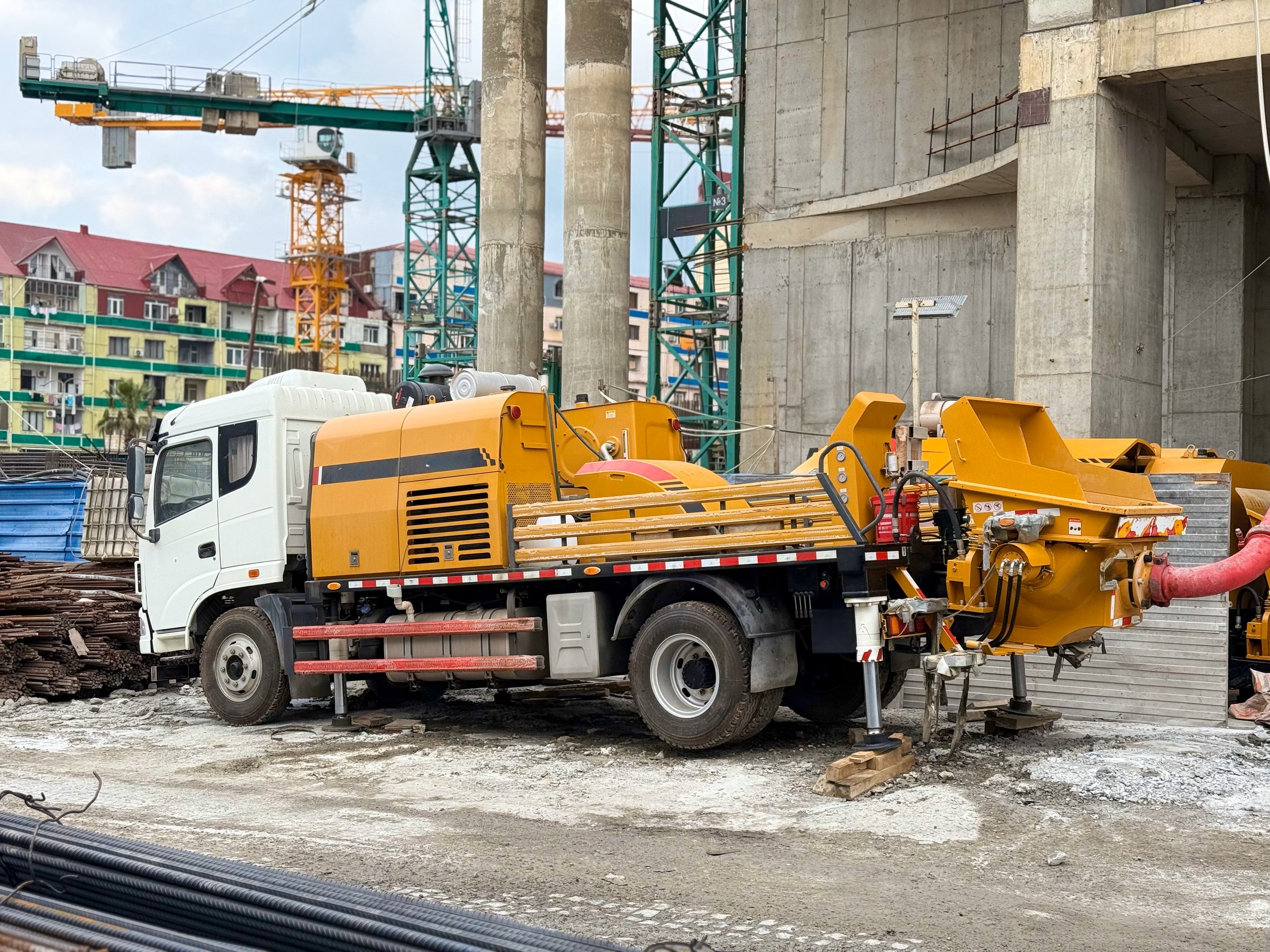 Concrete Pump Truck at Active Construction Site with Cranes and Materials. High quality photo