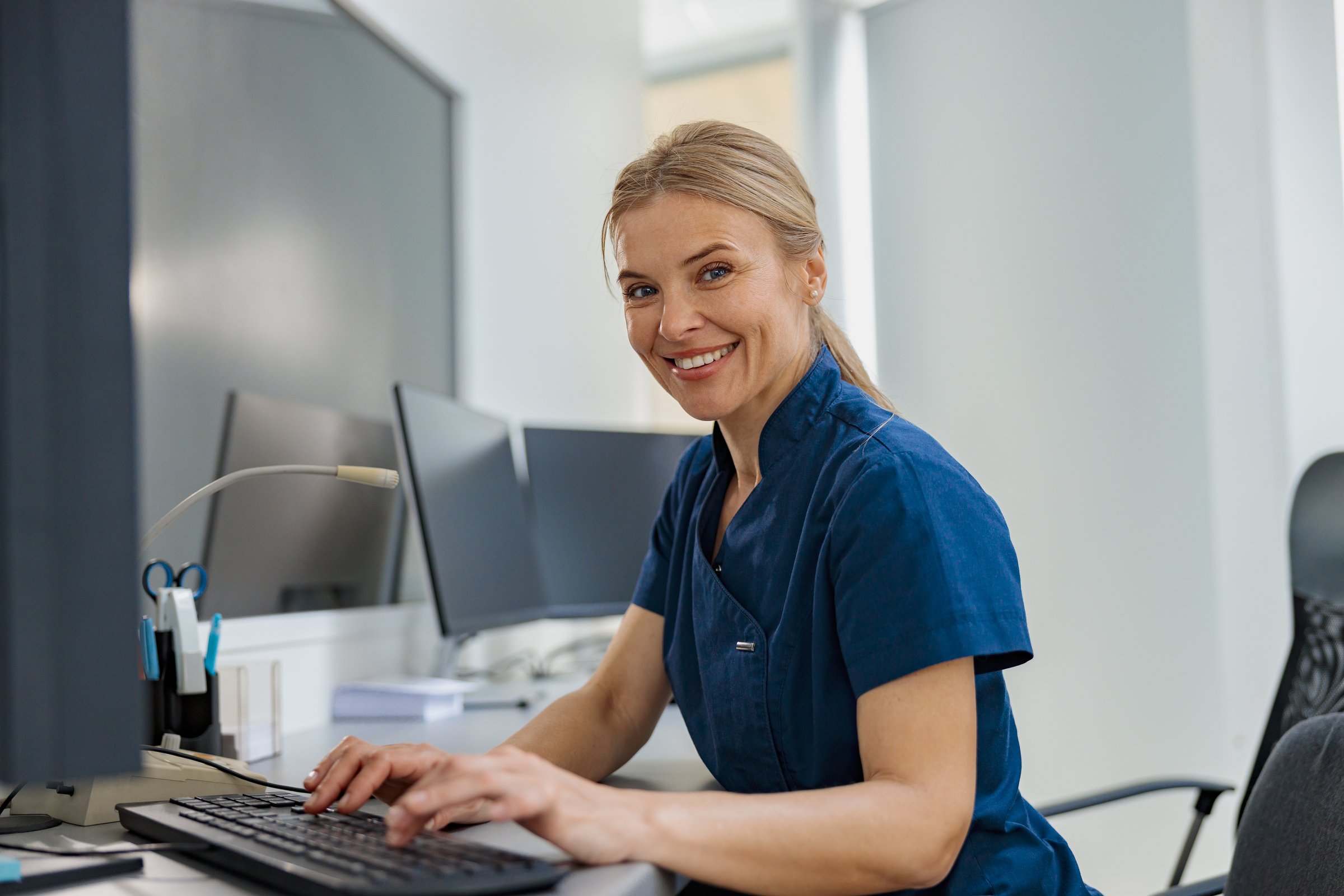 Nurse on Duty working on computer at the Reception Desk in modern clinic. High quality photo