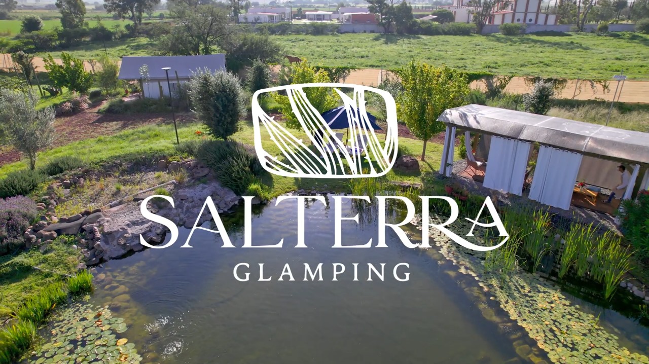 Glamping site with pond, lush greenery, and tents. Overlay text reads Salterra Glamping. Scenic rural setting.