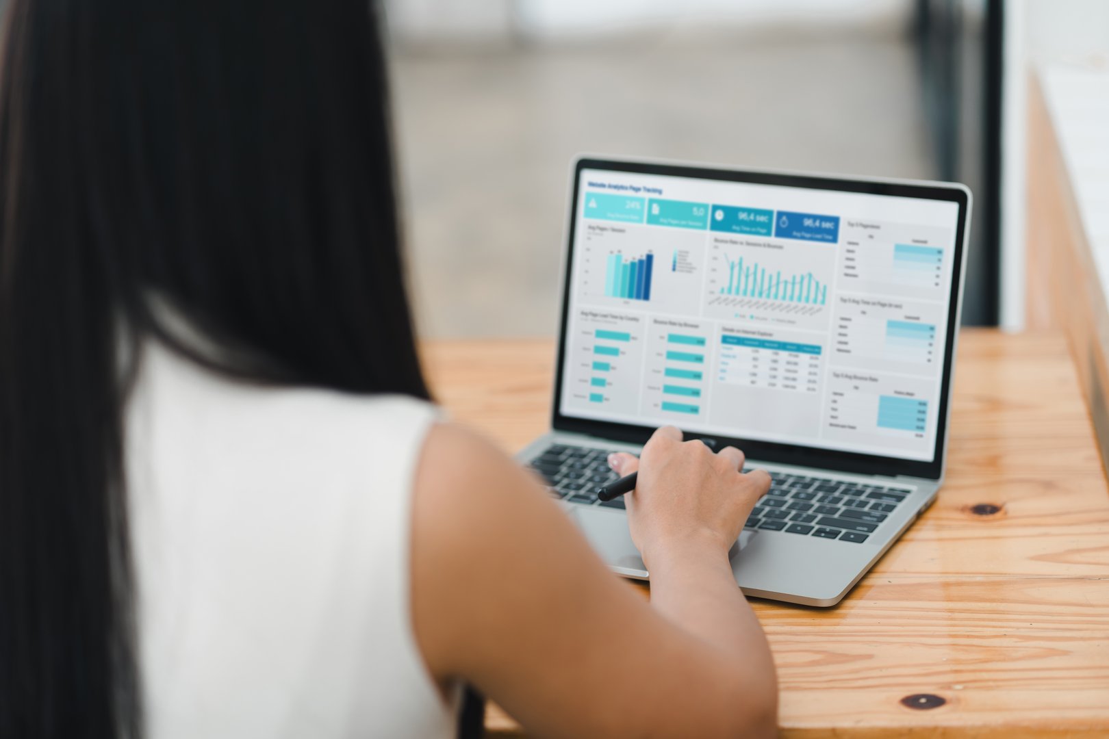 person analyzing data on laptop, focusing on various charts and graphs displayed on screen. setting suggests modern workspace, emphasizing productivity and technology.