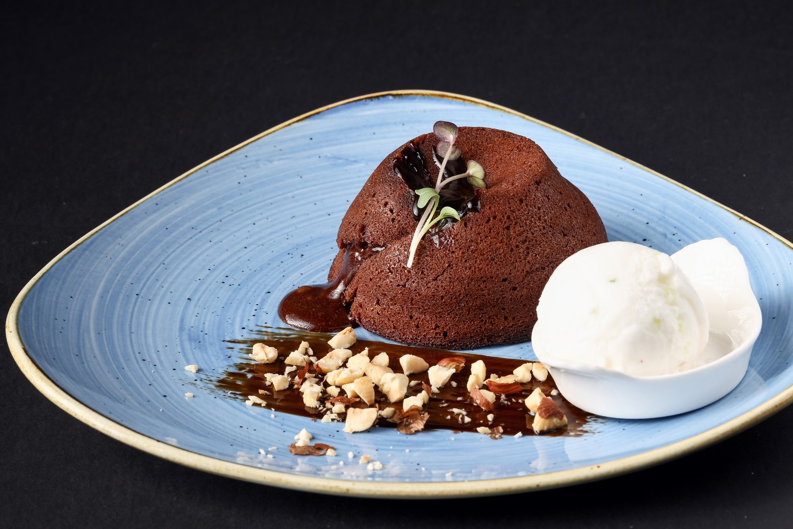 Chocolate souffle with nuts and vanilla ice cream on a plate.