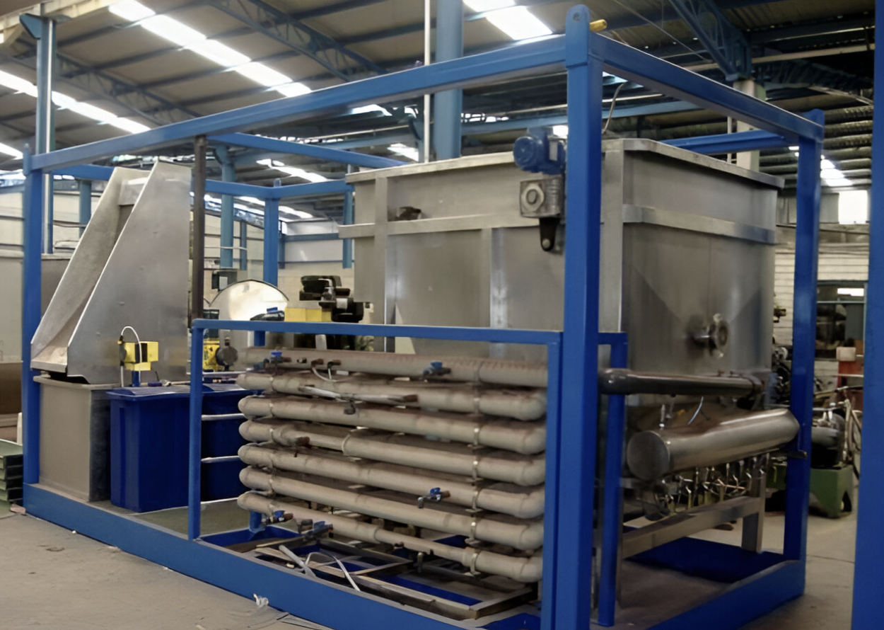 Industrial equipment in a factory, featuring a large metal tank and connected pipes within a blue metal frame structure.