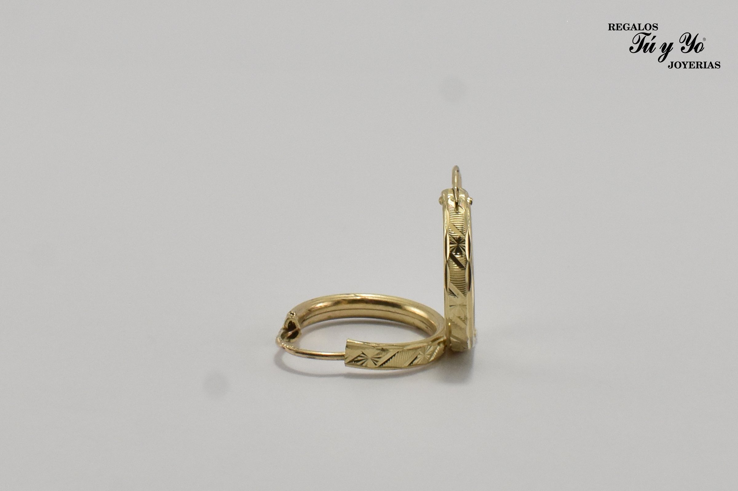 Gold hoop earrings with engraved patterns on a plain background, displayed partially opened.
