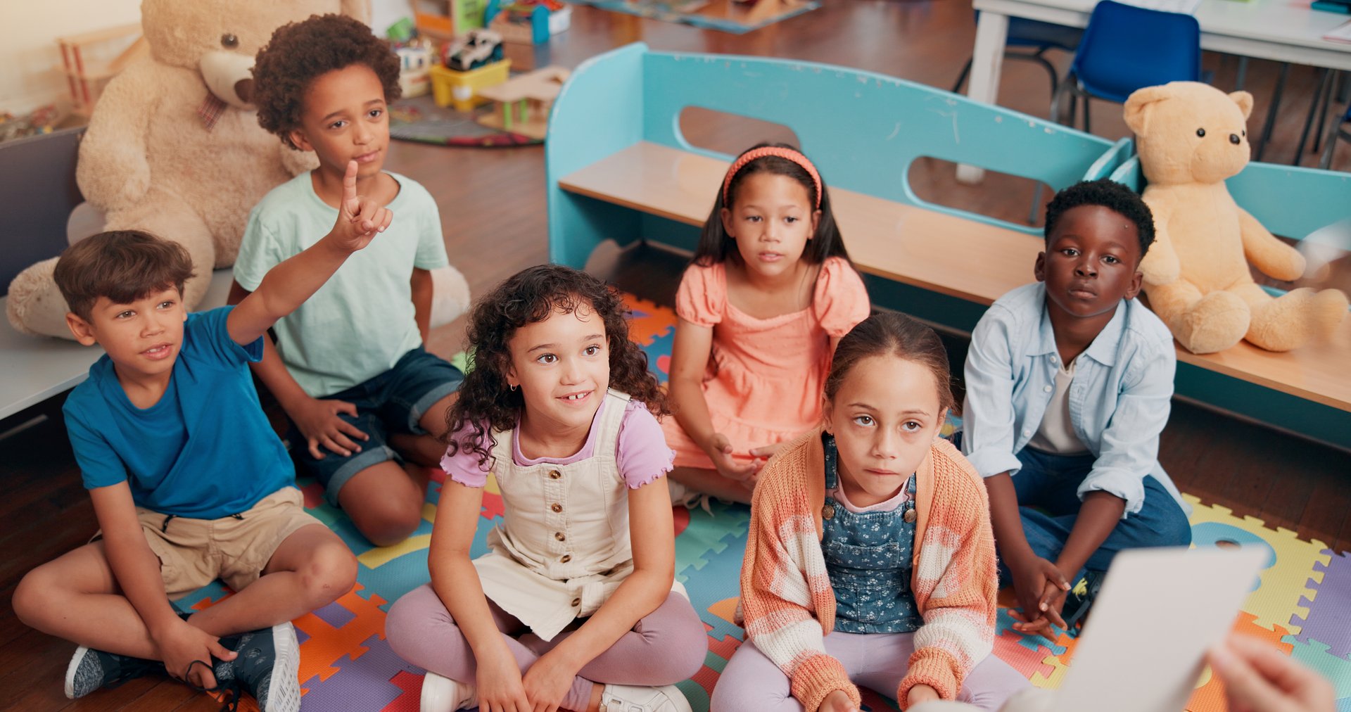 School, classroom and children with question for teacher for reading lesson, education and learning language. Youth, students and kids on floor with educator for story time, development and knowledge