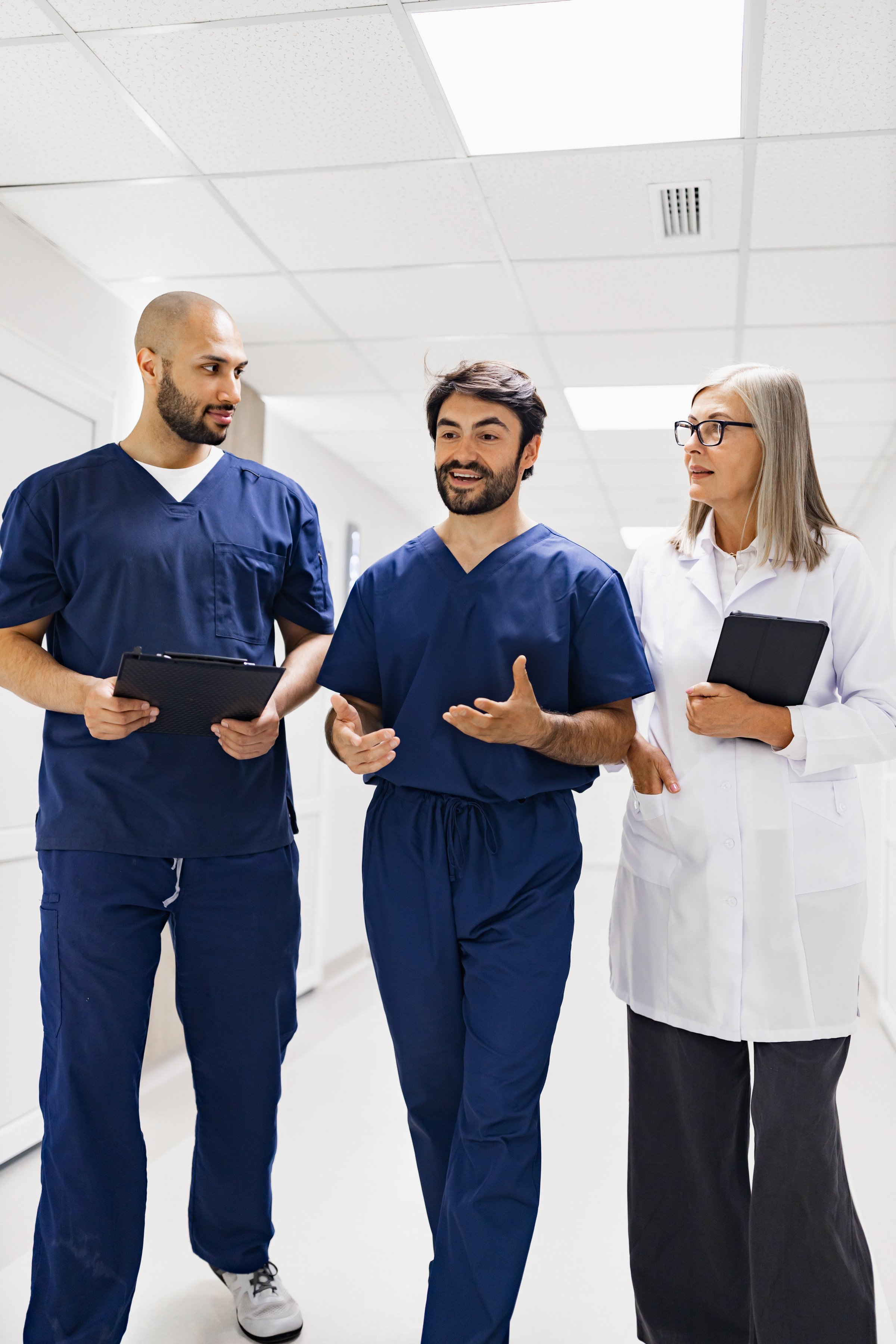 Medical professionals walking and discussing in a clinic hallway. A doctor and nurses are collaborating.