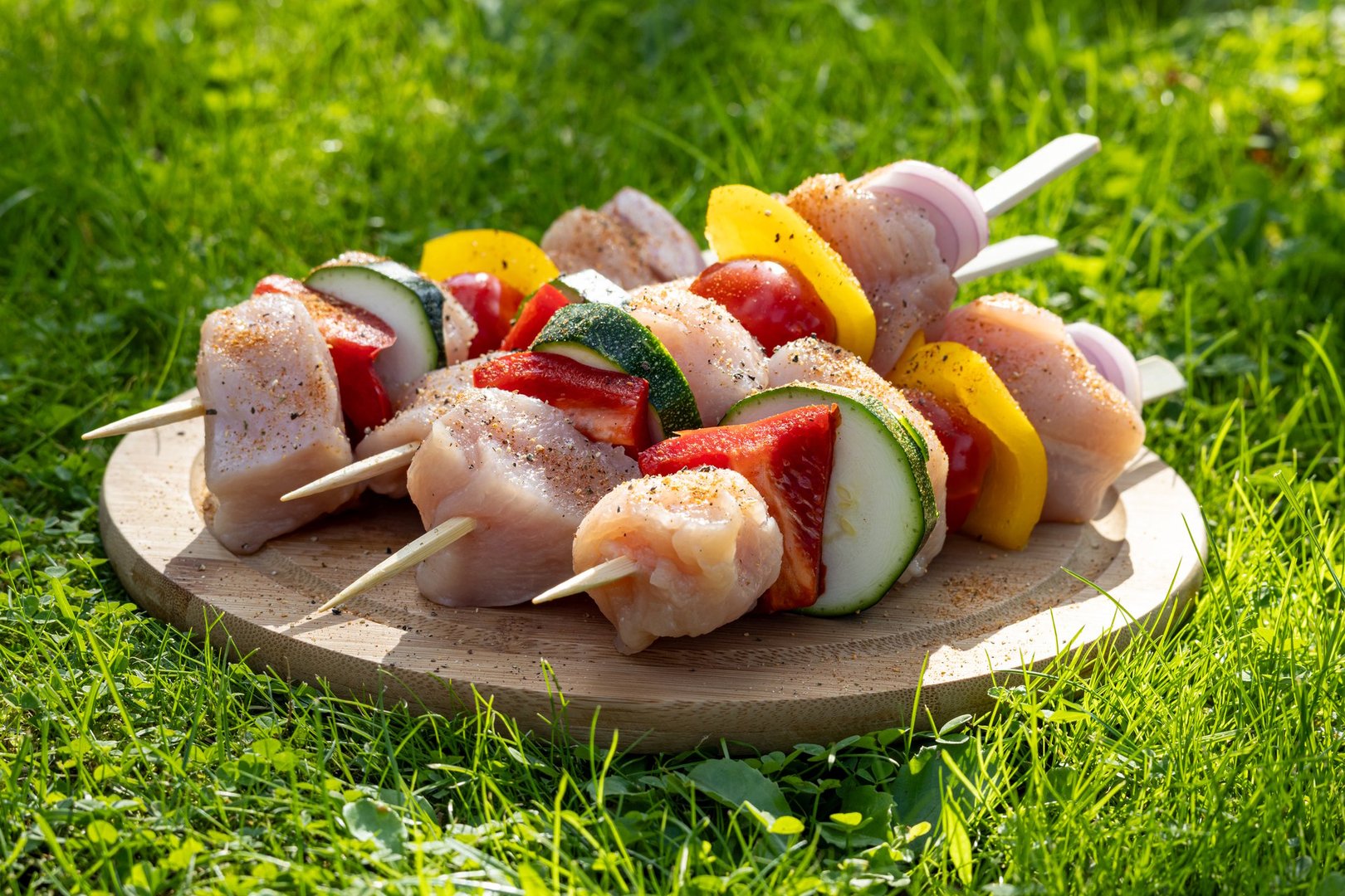 fresh raw chicken meat and vegetable skewers on wooden cutting board ready for grill