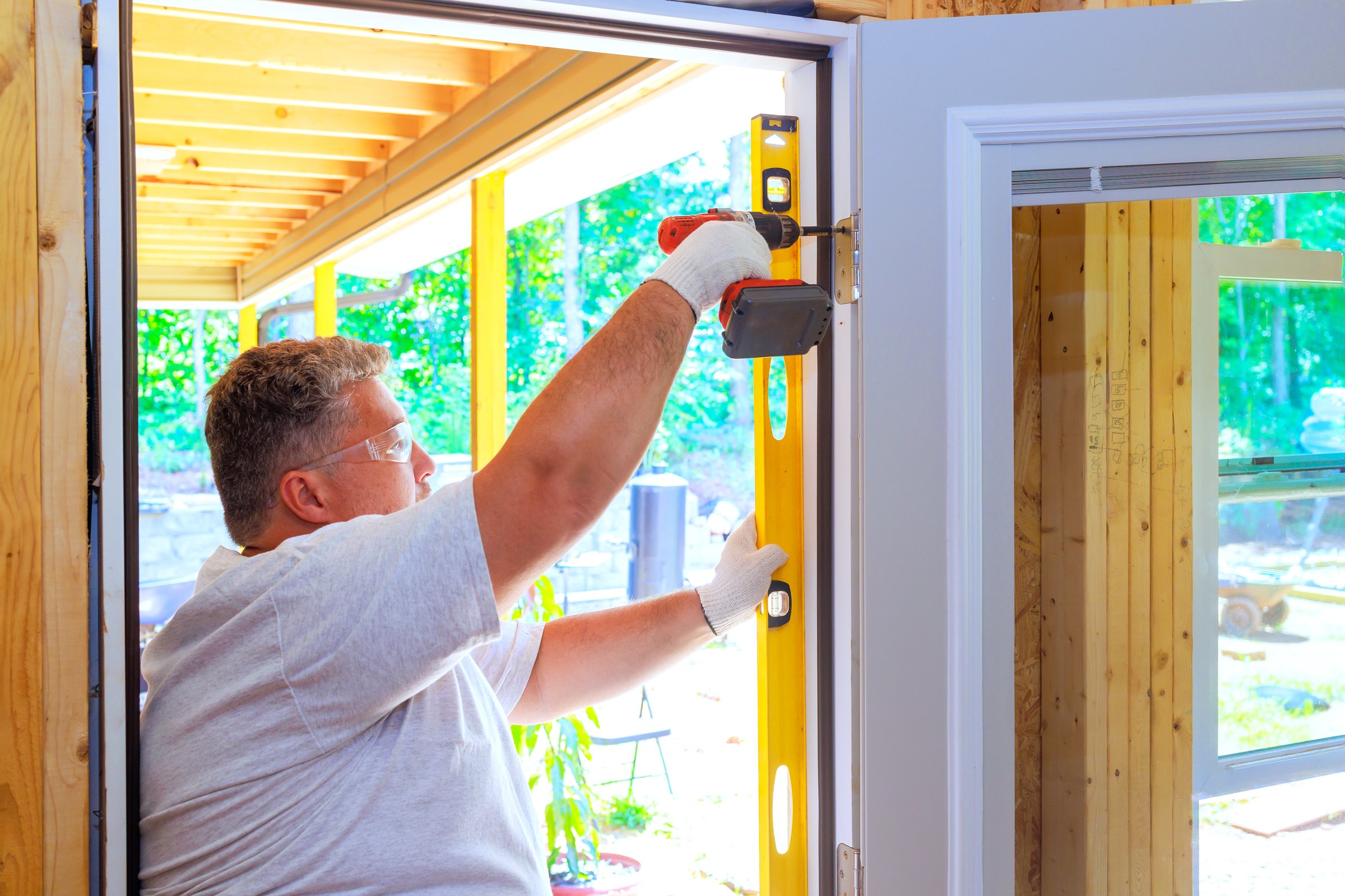 Professional carpenter worker installs front door of new house