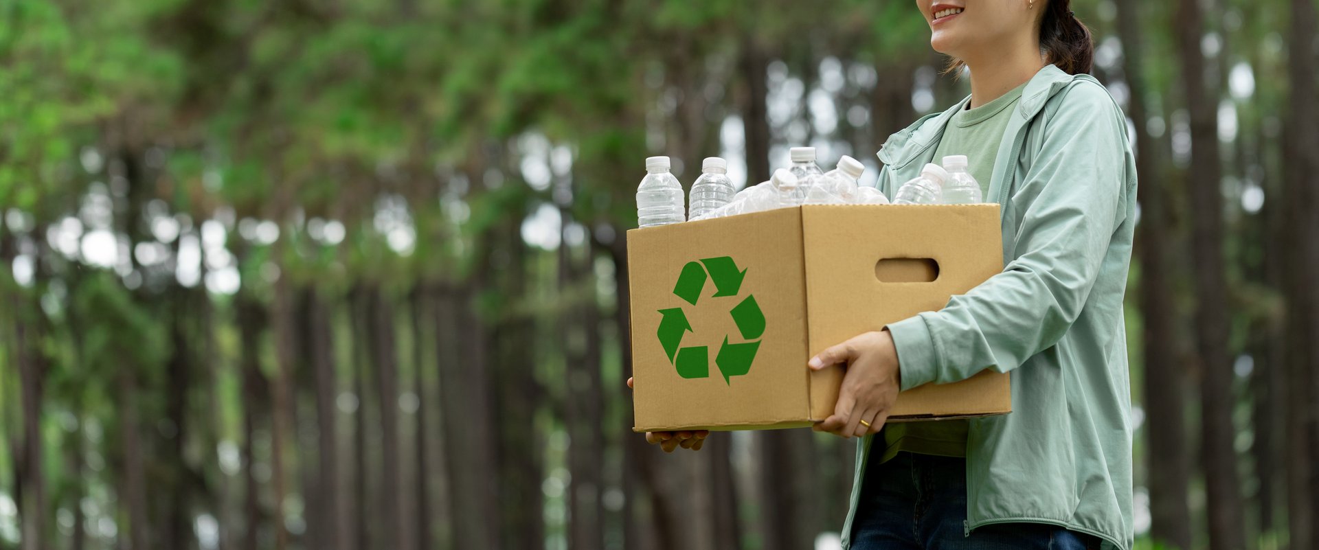 Recycling concept. Women holding a cardboard box with a water bottle with a recycling symbol. Management for a sustainable environment. Save the Earth Environment World. Net Zero. Reuse reduce recycle