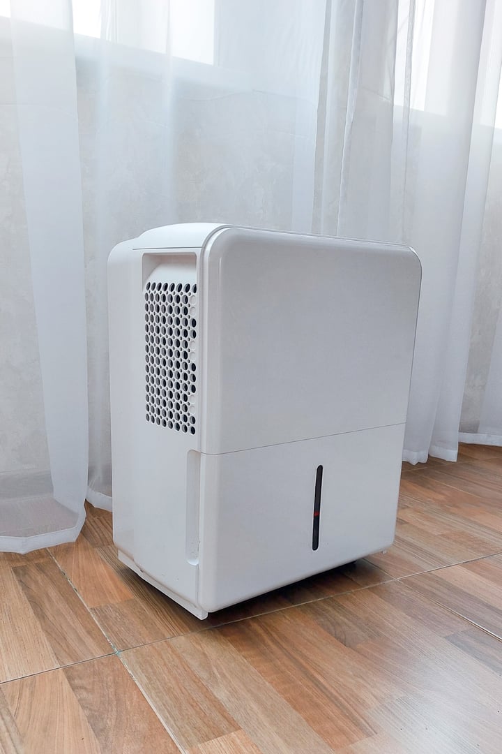 White dehumidifier standing on a wooden floor, reducing humidity and improving indoor air quality