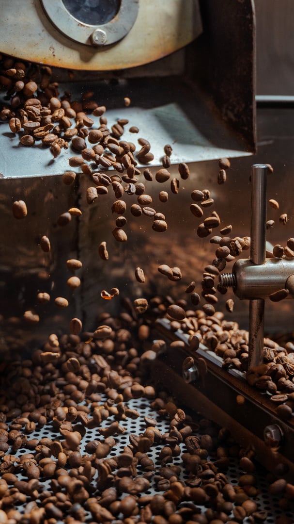 Coffee beans falling from a roasting machine into a cooling tray