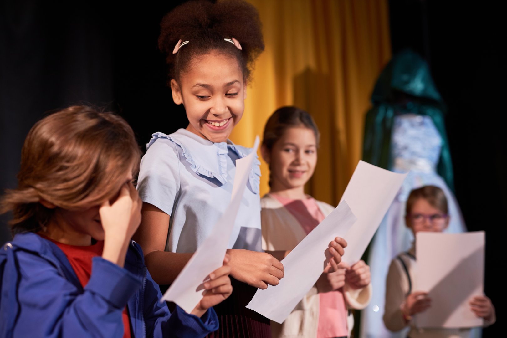Waist up portrait of smiling young girl looking at little boy while rehearsing school play together